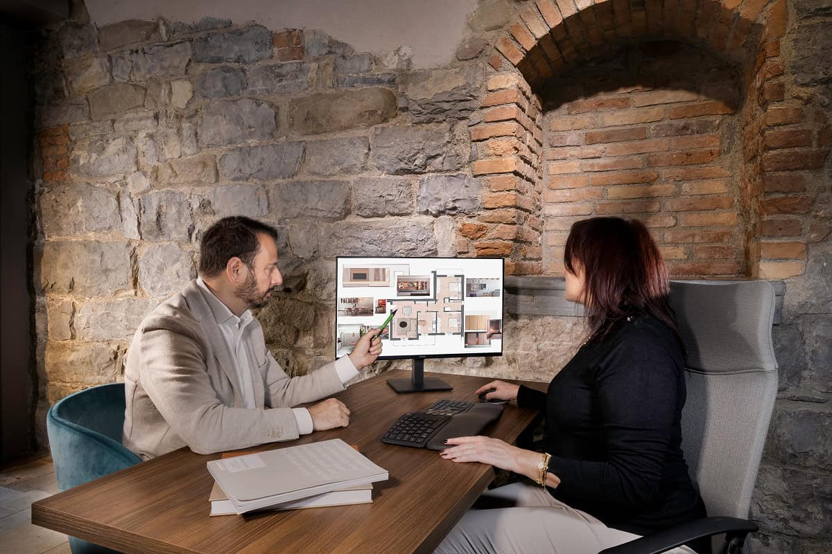 A man and a woman talking in front of a computer.